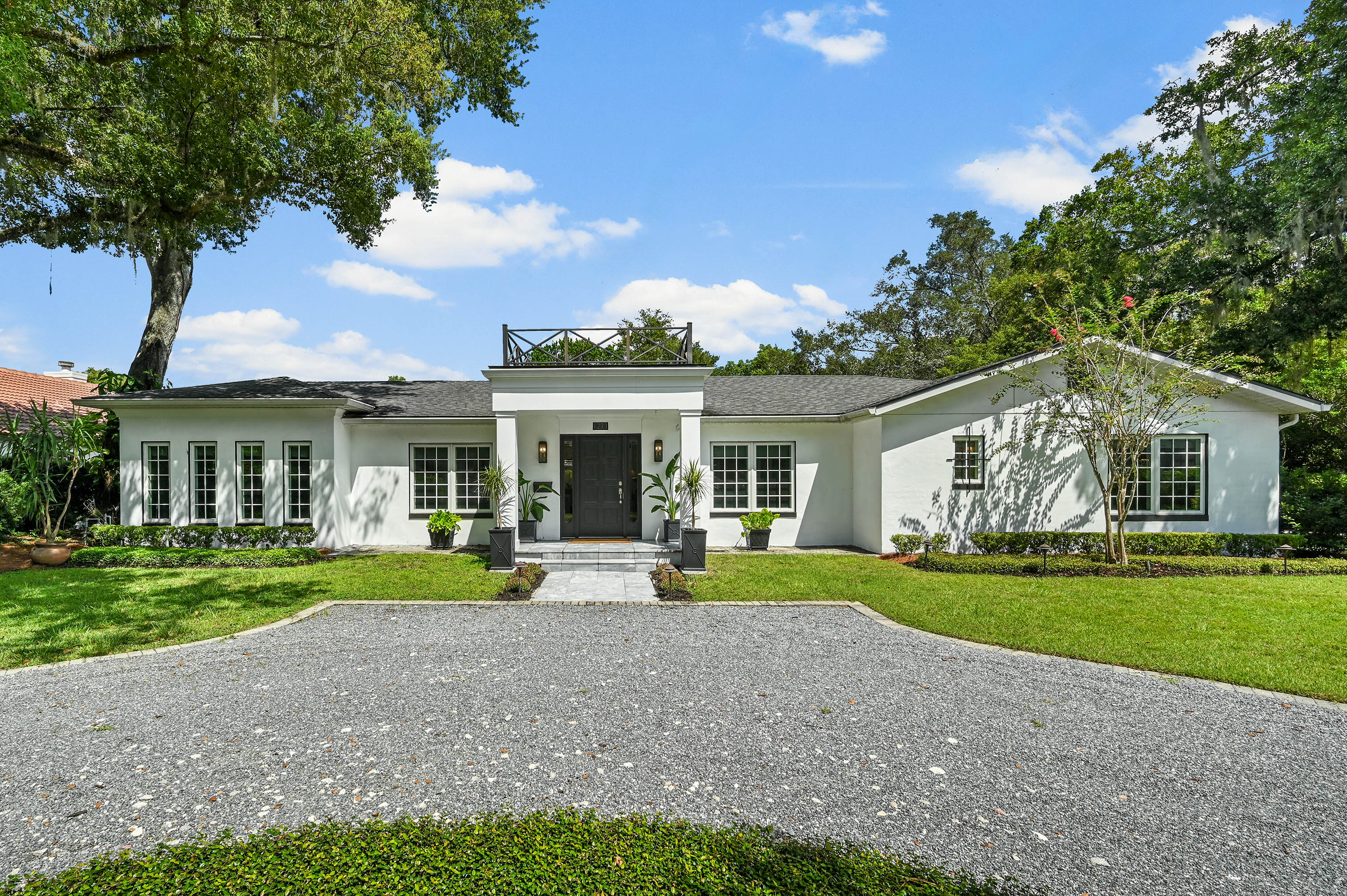 White single-story luxury home at 1271 Palmer Avenue Winter Park with circular gravel drive